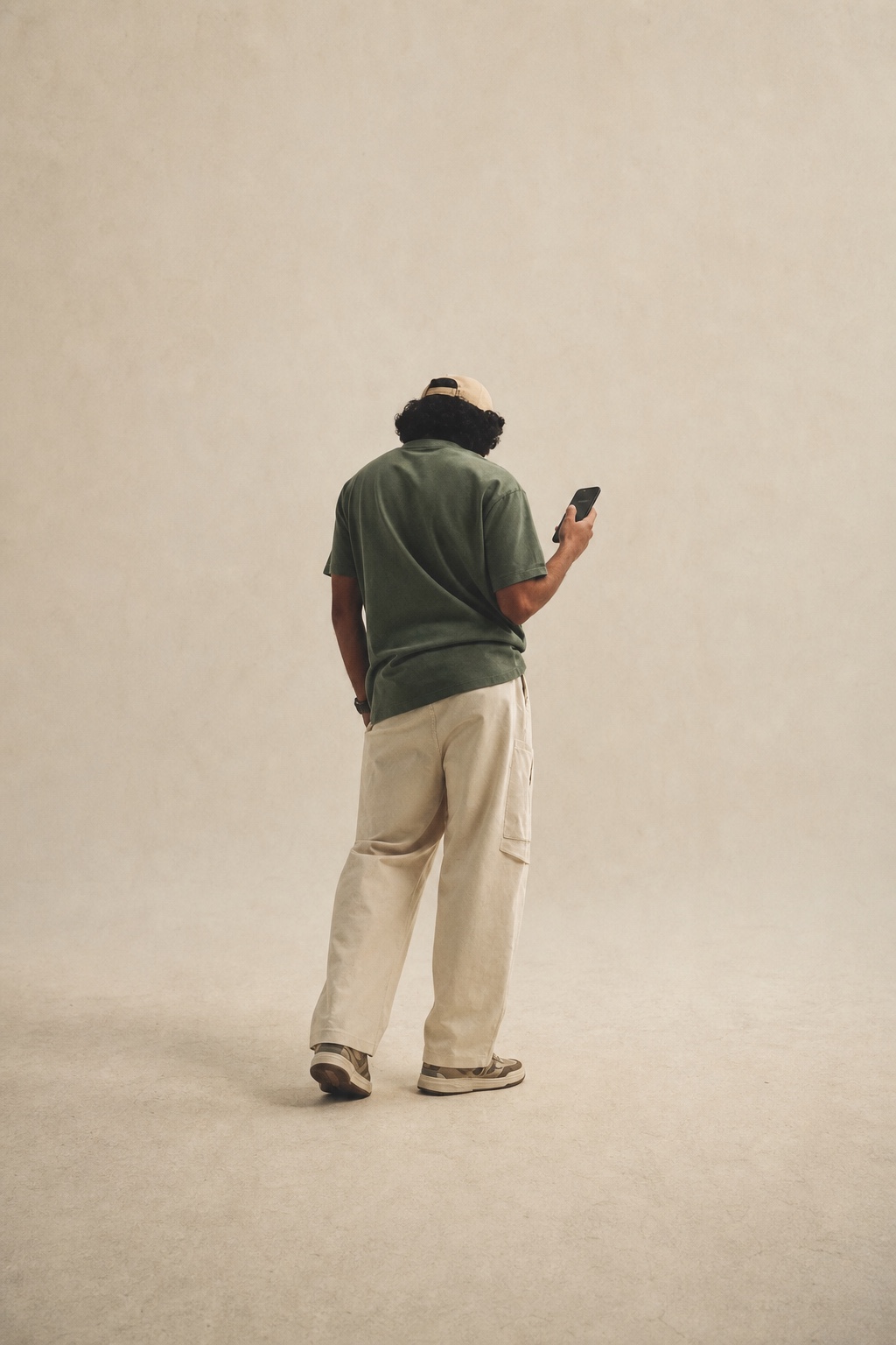 Eine Person steht allein im Raum und schaut auf ein Mobiltelefon.